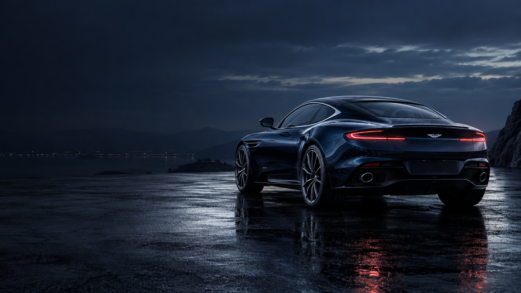 Rear three-quarter view of a midnight-blue Aston Martin on dark wet tarmac